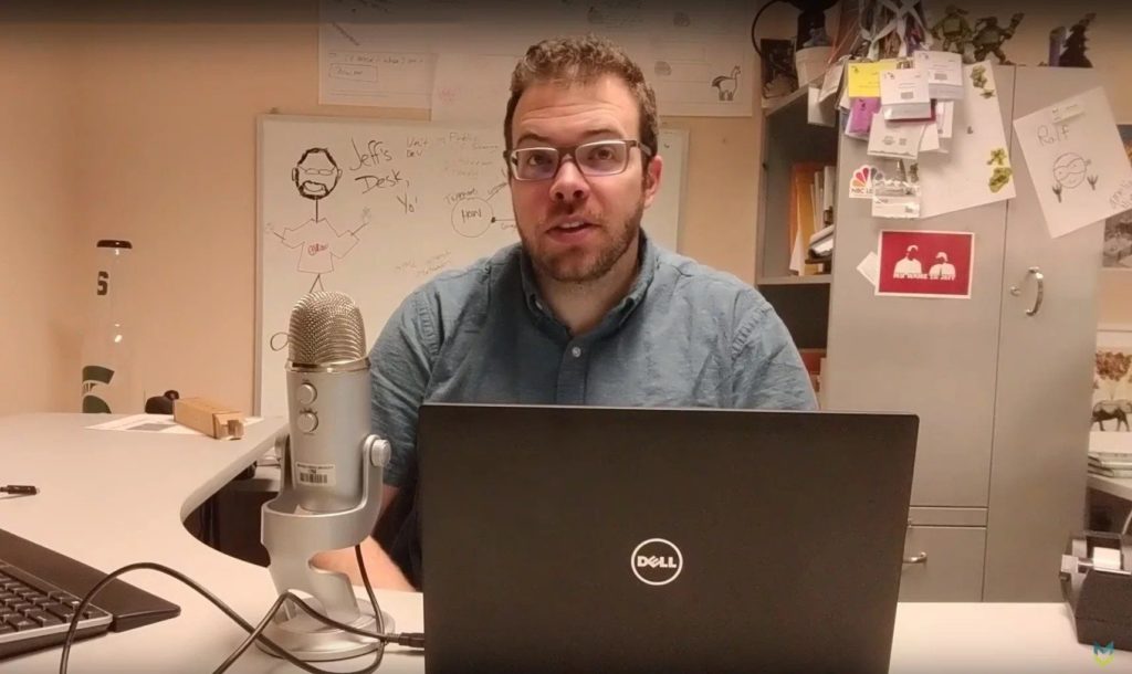 Jeff Gerlach sitting at his desk with a laptop and microphone