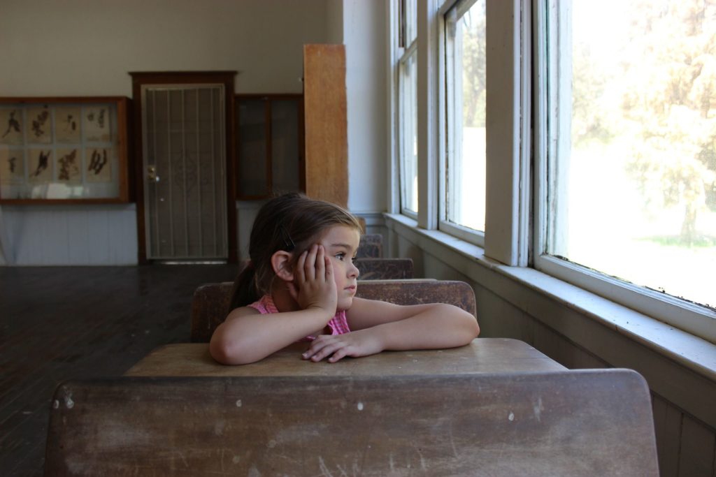Child staring out a window in a classroom